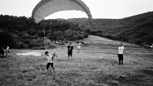 在伊卡洛斯·中国青岛国际飞行节，伞友驾驶滑翔伞从山上飞下。受访者供图